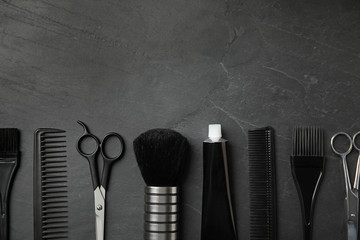 Professional tools for hair dyeing on black stone background, flat lay. Space for text
