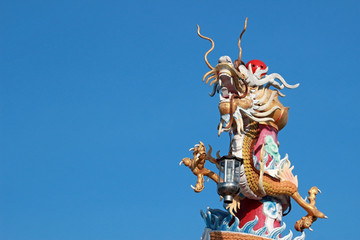 Fototapeta na wymiar Decorative dragon sculpture with lantern adorns a pole at a Chinese temple in southeast Asia