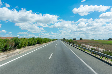 Empty highway with a blue sky and cotton clouds