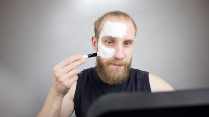 a man puts a mask on his face by the mirror himself