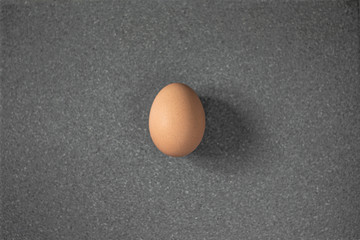 One beige egg lies on a gray granite surface.