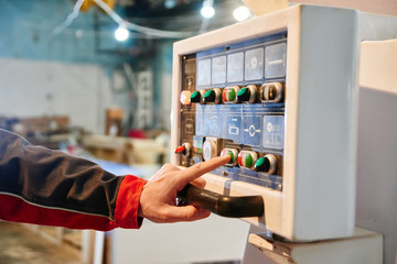 Hand presses a button on the control panel close-up. Concept automated manufacturing factory, modern production technologies