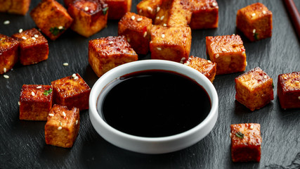 Fried Tofu with chopstick and sesame seeds on rustic stone board