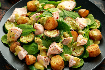 Salmon, new potato, courgette and spinach salad on wooden table