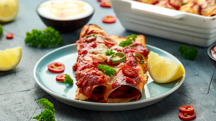 Baked Chicken fillets enchiladas with courgette, salsa sauce and cheese served with lemon wedges and chilies
