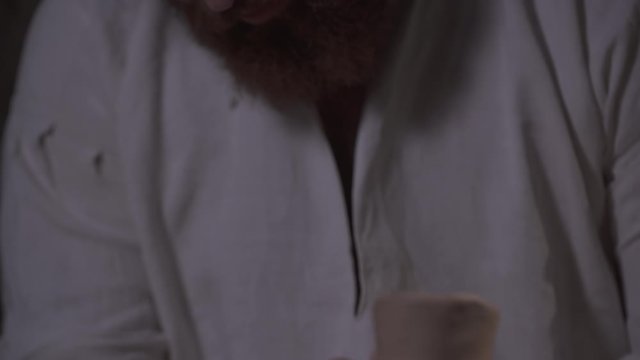 Close-up of a Potter's heary face who is making a jug of clay when camera tilts down