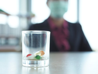 Tablet,drug,pill on the table and blur background business woman is wearing mask for protection from coronvirus or covid-19 or pm 2.5.
