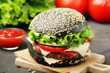 A black burger with vegetables and beef meat	