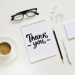 Workspace with pen, paper, coffee cup and office supplies.