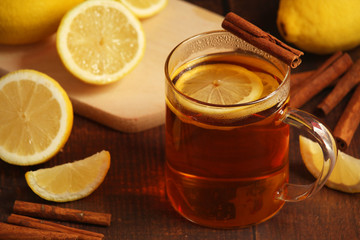 A mug with hot tea with lemons and cinnamon sticks	