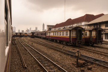 Fototapeta premium Old trains on a hazy day in Bangkok central train station. Skyscrapers in distance. Arrival from Don Mueang International Airport. No sunlight,