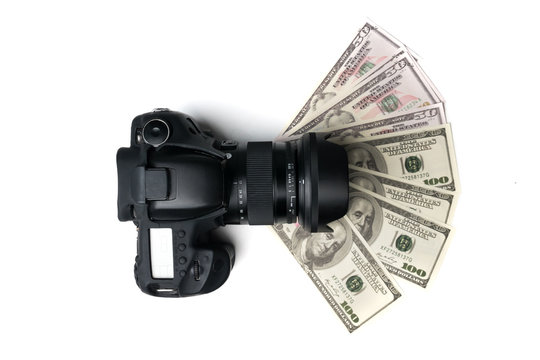 Top view of a black digital camera on banknotes with white background.