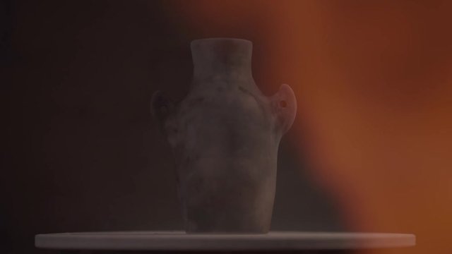 A jug of clay being burnt with fire flames on a dark background, VFX