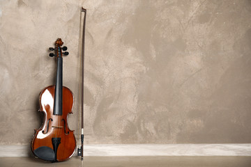 Classic violin and bow near beige wall. Space for text
