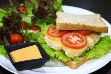 Club Sandwich with Chicken, PIckled Cucumber, Tomato and Smoked Meat. Garnished with sauce on wooden table