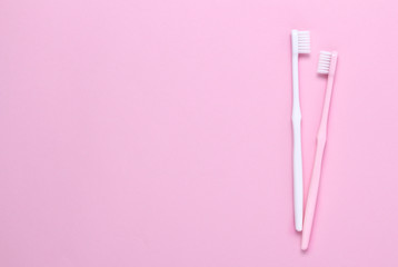 Pink and white toothbrushes on blue background. Taking care of teeth, dental concept. Flat lay photo, copy space, top view.