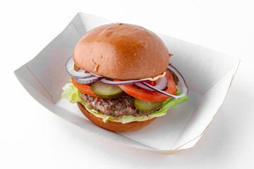 Tasty hearty hamburger with vegetables, cheese and herbs in eco paper packaging for take away or food delivery isolated on a white background.