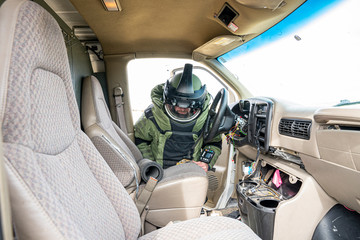 A bomb technician in a full bomb suit searches a vehicle for improvised explosive devices