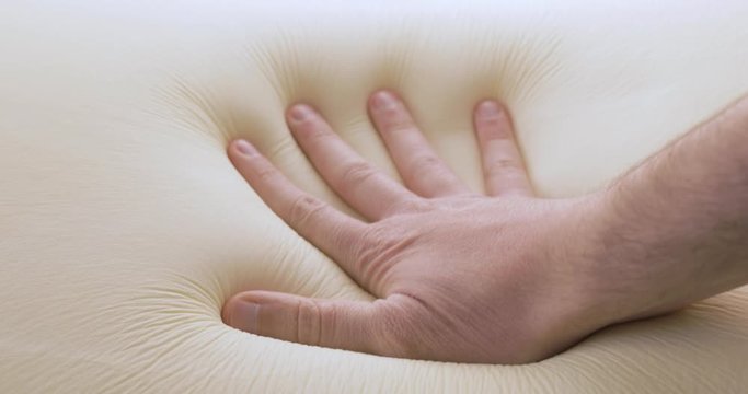 Mano sta toccando un materasso in poliuretano con tecnologia memory foam.