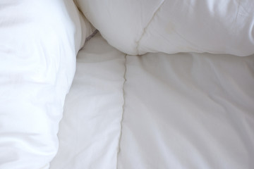 Soft white blanket. The sun's rays fall on the bed linen. Cosiness