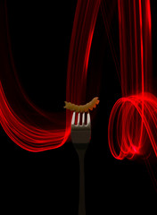Macaroni strung on a fork on a black background with a red light line