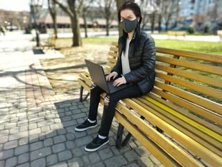 A girl in a fabric mask works remotely; freelance during quarantine is a coronavirus pandemic....