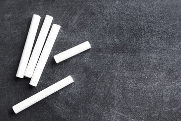 Pieces of white chalk on blackboard, flat lay. Space for text