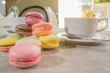 Multi-colored macarons with cappuccino on a table in a coffee shop. Sweet and tasty food