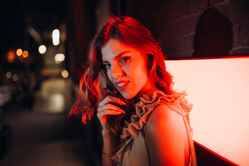 Naklejka premium a young girl in a summer dress walks around the city at night