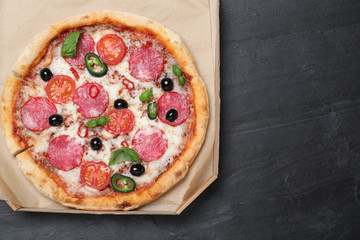 Delicious pizza Diablo in cardboard box on dark background, top view. Space for text
