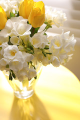 Beautiful bouquet with fresh freesia flowers in vase on table near window