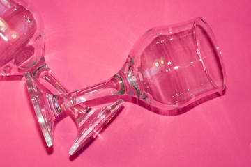 Glass transparent wine glasses on leg on pink background. Highlights and shadows on the dishes.