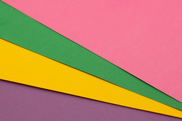 Multi colored paper background of pink, green, yellow and purple.