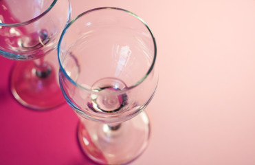 Glass transparent wine glasses on leg on pink background. Highlights and shadows on the dishes.