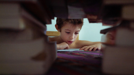 Niño lee y estudia detras de libros