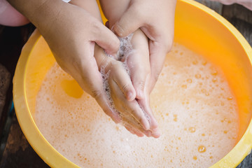 Hands of mother assisting child while washing hands with soap to prevent virus and bacteria for corona virus (covid19) protection.