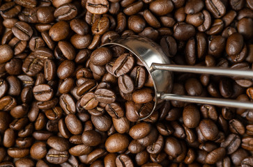 Coffee beans with metal measuring spoon. Close-up