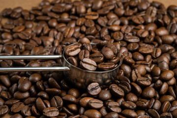 Coffee beans and metal measuring spoon filled with coffee. Close-up