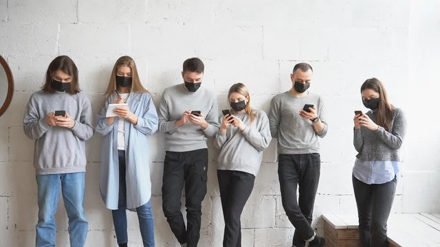 Group of young caucasian people in protective medical mask, they take care of health, afraid of coronavirus infection. COVID-19 disease global problem. People stand in a line