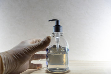 Human hand with disposable glove in motion to hold alcohol gel in Covid 19 prevention