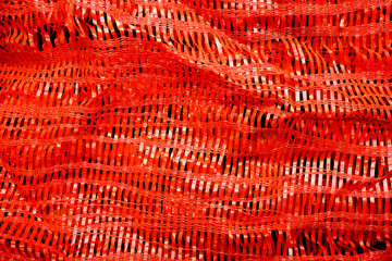 Fototapeta premium Red synthetic woven texture. Woven background in Lash Lava. Synthetic sack texture.