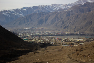 Mountain lake, hills covered green grass on snowy rocky mountains background. Caucasus peaks in Georgia. Amazing view on wild georgian nature. Landscape of the rocky Caucasus mountains