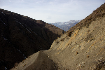 Mountain lake, hills covered green grass on snowy rocky mountains background. Caucasus peaks in Georgia. Amazing view on wild georgian nature. Landscape of the rocky Caucasus mountains
