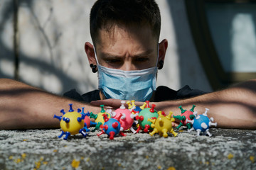 Caucasian guy with a protective mask and looking at virus models. The concept of Coronavirus