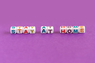Phrase Stay At Home made out of colorful beads on purple background	