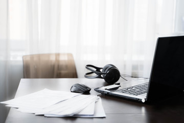Home workspace with laptop, computer mouse at telework due to quarantine of coronovirus pandemic COVID-2019. Remote work at home table.Online communication on headset, conference with boss,colleagues