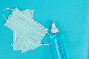 Surgical mask and spray alcohol for hand hygiene on blue background.for the prevention of the flu and the Coronavirus, covid-19. Health care concept.Top view
