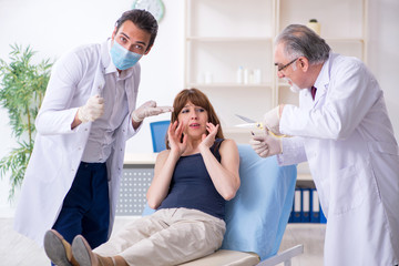 Two male doctors and young woman in plastic surgery concept
