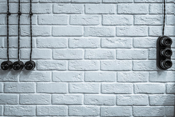 White brick textured wall, with sockets, switches and electrical wiring. rustic stylish background, copy space