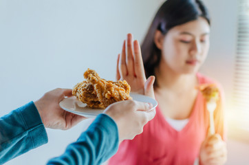 hand of friend send delicious fried chicken with happy young pretty woman slim body refuse to eat...